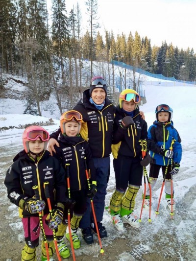 Czworo dzieci w strojach narciarskich, pomiędzy ni