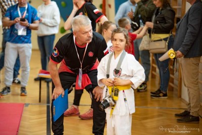 Mężczyzna pochyla się nad zwadoniczką karate z żółtym pasem